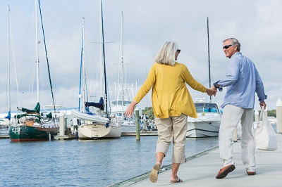 happy retired couple holding hands in a marina