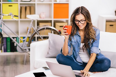 woman drinking coffee working at laptop